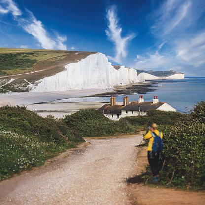 Shot of a woman taking pictures with her camera outside. Seven Sisters country park tall white chalk cliffs, East Sussex, UK