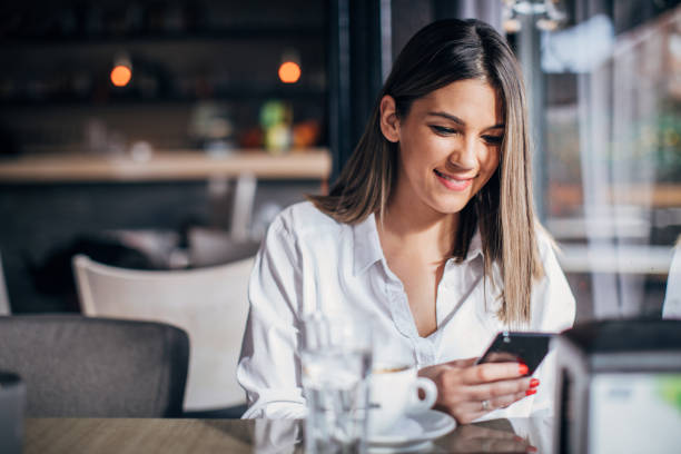 istock Young woman sitting in cafe and using smart phone 1251311053