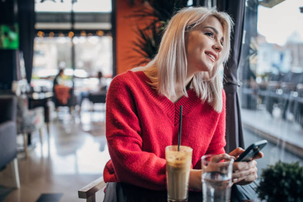 istock Young woman sitting in cafe and using smart phone 1251311164