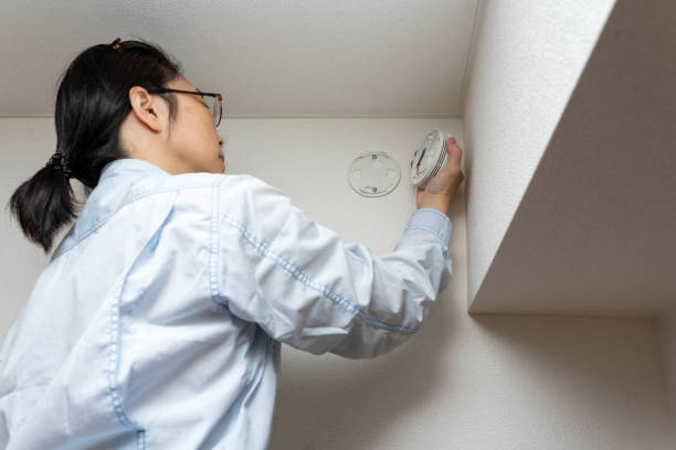 Woman checking house equipment Japanese woman checking house equipment, smoke, fire detector. smoke detector photos stock pictures, royalty-free photos & images