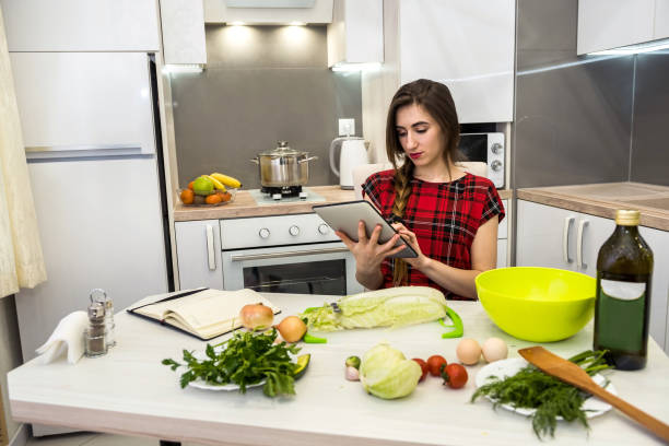 istock Young woman using a tablet computer to cook different vegetables in her kitchen for everything about healthy nutrition. 1251311428