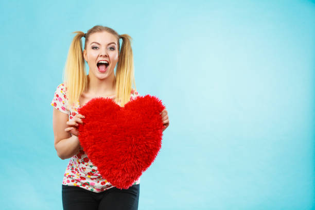 istock Happy woman holding heart shaped pillow 1251312143