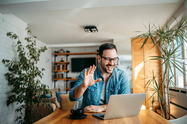 Smiling man having video call over laptop computer, at home, portrait.