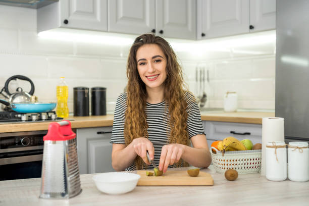 istock Smile young woman cooking fresh salad with fruit in kitchen 1251315842