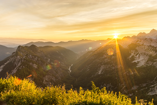 Great sunrise in the mountains. Back light Sun with nice colorful lens flares and sunbeams. Julian Alps, Triglav National Park, View from Mountain Slemenova Spica Sleme to Mount Skrlatica, Slovenia.
