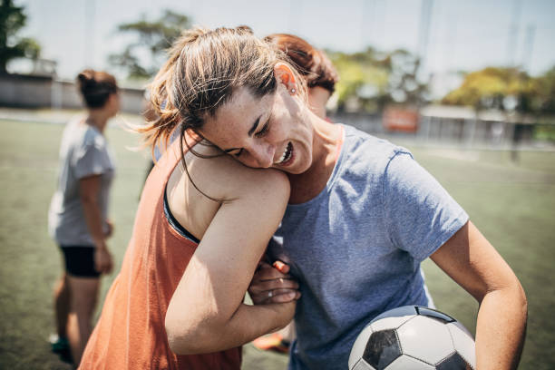 Women huging outdoors on a soccer field