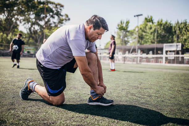istock Men tying shoelace outdoors on soccer field 1251323174