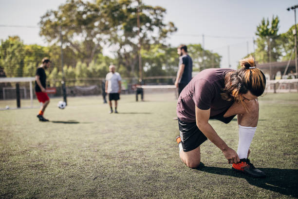 istock Men tying shoelace outdoors on soccer field 1251323209