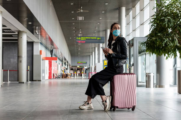 młoda kobieta na lotnisku z bagażem, ubrana w maski na twarz n95 - airport tourist airport lounge young men zdjęcia i obrazy z banku zdjęć