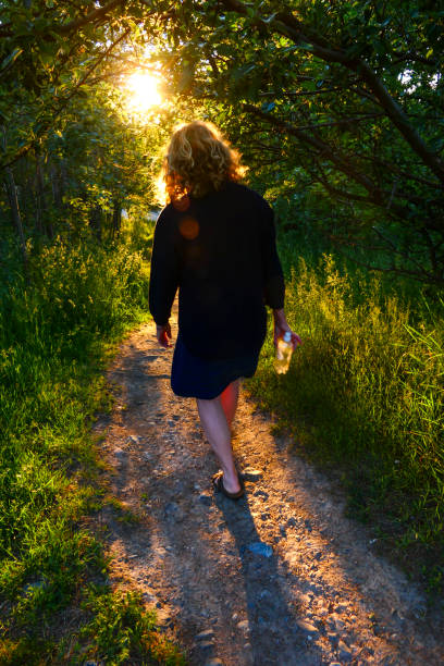 Stockholm, Sweden A woman walks down a beautifully lit path at sunset.