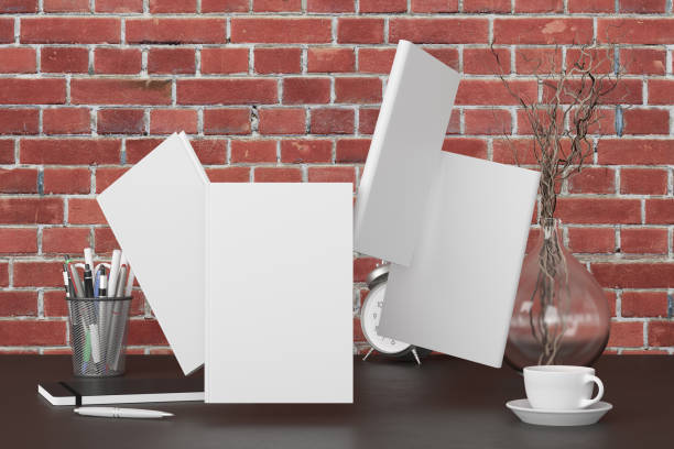 istock Blank book cover mock up flying over desk in office workspace. 1251324631