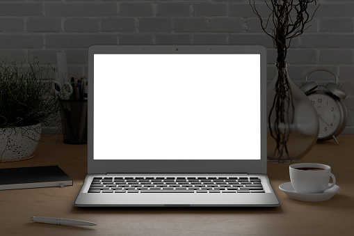 Workplace with glowing laptop screen at evening mock up. Wooden desk and white brick wall. Front view. Clipping path around laptop screen. 3d illustration
