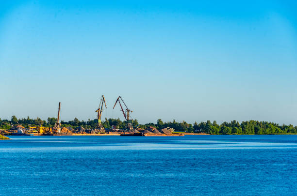 речная набережная с кранами для разгрузки барж. - barge beach large blue стоковые фото и изображения