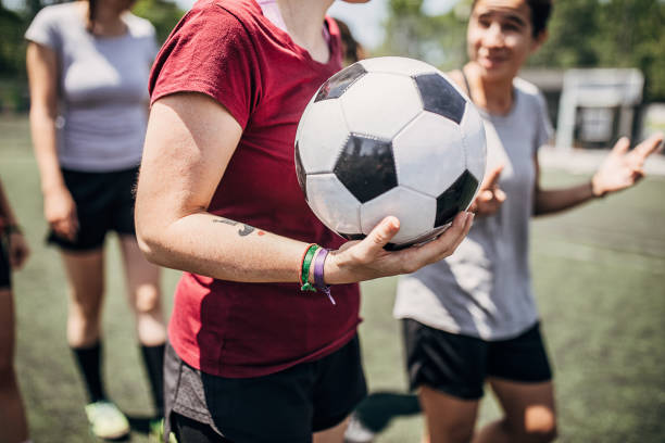 Female soccer players on soccer field Group of women, female soccer players, enjoying time together outdoors on soccer field. Focus on soccer ball in female hand. football player girlfriend stock pictures, royalty-free photos & images
