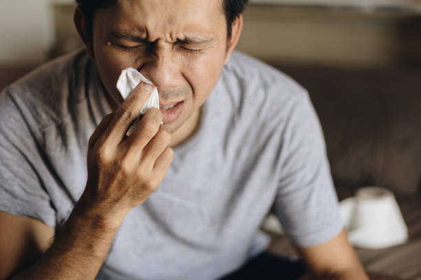 Young asian man sick wiping and cleaning nose with tissue stock photo