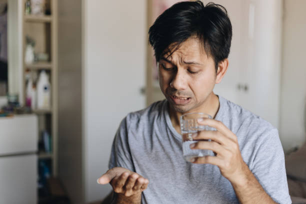 istock Young asian man taking pills in bedroom 1251325845