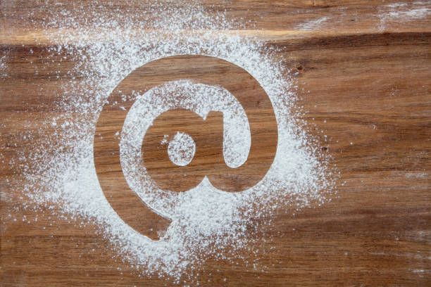 istock @ symbol stencil in flour on a wooden board 1251326438