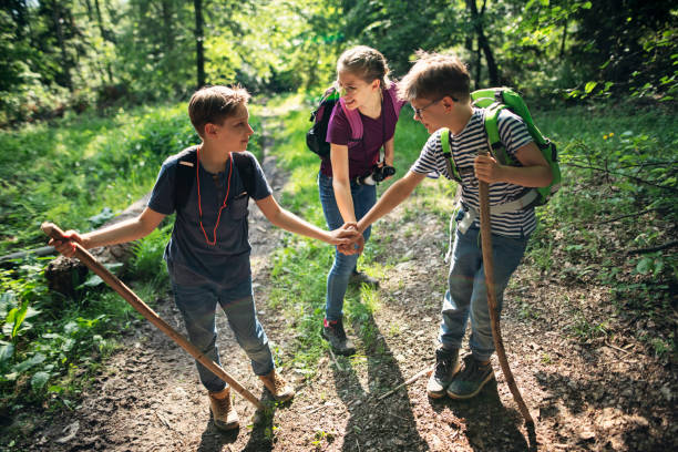 istock Happy kids hikers stacking hands in forest 1251329231