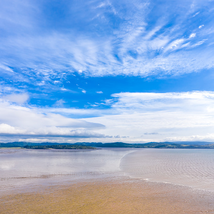 The view on a bright sunny summer day across Auchencairn Bay. The location is in Dumfries and Galloway south west Scotland. Beyond the bay is the Solway Firth, a stretch of water between the north west coast of England and the south west coast of Scotland.\nThe image was captured by a drone flying at a low altitude.