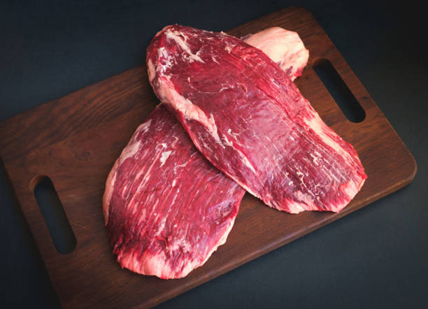 raw flank beef on a wooden Board top view raw flank steak beef on a wooden Board on dark background flank steak stock pictures, royalty-free photos & images