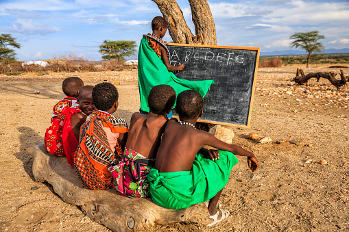 African children  from Samburu tribe during English language class under the acacia tree in remote village, Kenya, East Africa. Samburu tribe is one of the biggest tribes of north-central Kenya, and they are related to the Maasai.
