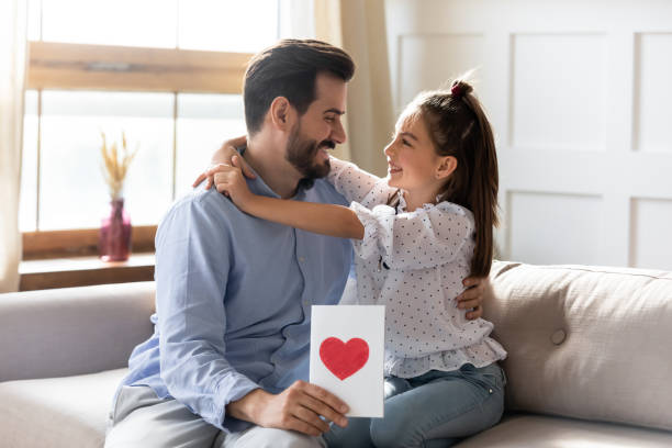 istock Pretty girl hugging, congratulating father, presenting greeting card 1251332372