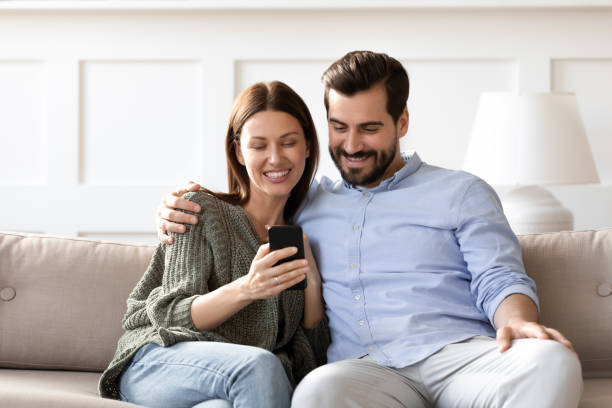 istock Smiling man and woman hugging, using smartphone together, having fun 1251332419