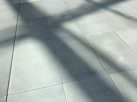 Clean ceramics tiled floor with sunlight and shadow