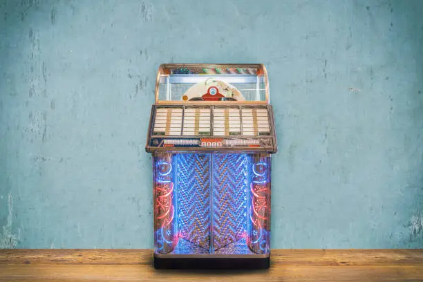 Colorful vintage jukebox in front of a blue weathered wall on a wooden floor