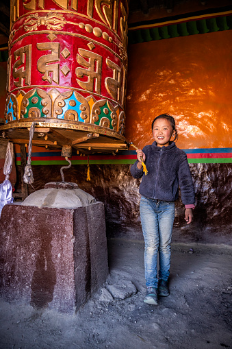 A young girl turning the prayer wheels, Lo Manthang in Upper Mustang. Mustang region is the former Kingdom of Lo and now part of Nepal,  in the north-central part of that country, bordering the People's Republic of China on the Tibetan plateau between the Nepalese provinces of Dolpo and Manang.