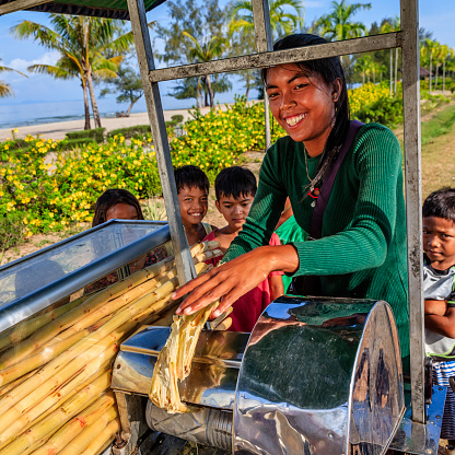 Cambodian young woman preparing a fresh sugar cane juice on the beach, Cambodia