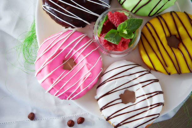 Doughnuts with multi-colored glud on white tablecloths and raspberries