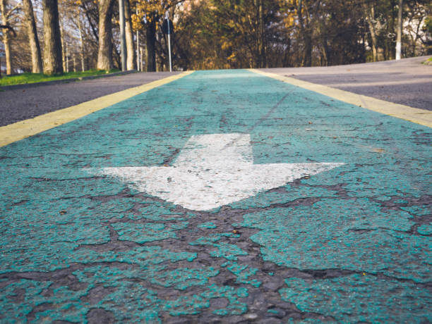 istock An arrow on a bicycle path. Green bicycle lane with a white arrow. 1251335435