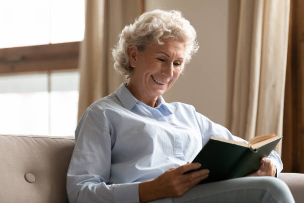 istock Smiling mature woman enjoy free time reading interesting book 1251337458