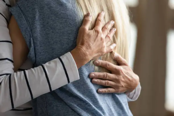 Close up image elderly woman hugs younger relative girl. Grown up adult daughter or granddaughter enjoy moment cuddle to old mom or aged granny. Family bond, together in trouble and happiness concept