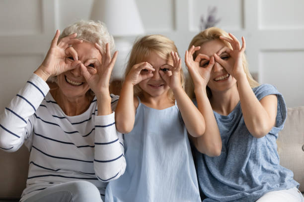 tres generaciones mujeres con los dedos haciendo binoculares como gafas de forma - senior women grandmother glasses senior adult fotografías e imágenes de stock