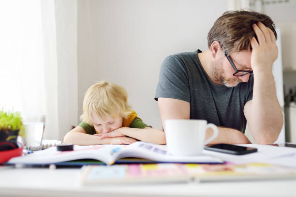 istock Tired and angry father trying help son doing his homework, but bored child refusing. Homeschooling, online studying, remote education for kids during quarantine is a problems for parents. 1251338649
