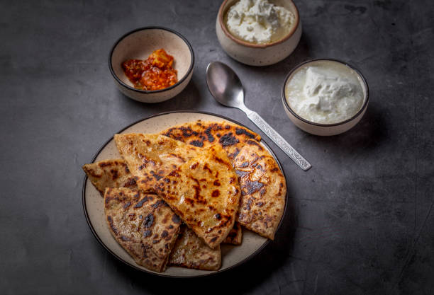 Aloo paratha or stuffed potato flatbread with curd, white butter and mango pickles