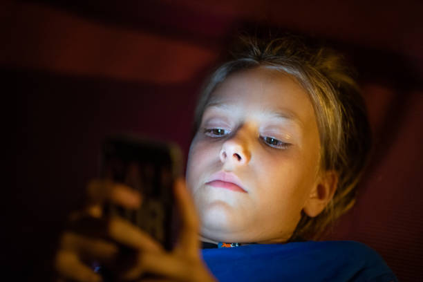 istock Young Girl Lying Down And Using A Mobile Phone In The Dark 1251342984