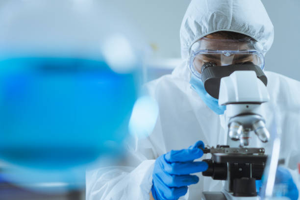 jeune scientifique asiatique beau homme ajuster la mise au point et utiliser microscope à la recherche de cellules biochimiques en laboratoire. médecin et scientifique travaillent en laboratoire pandémie de virus corona, concept covid19 - drug discovery photos et images de collection