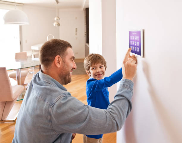 Father with son controlling smart devices with a digital tablet at home Father teaching his son controlling home with a digital touch screen panel. Concept of internet of things. smart home family stock pictures, royalty-free photos & images