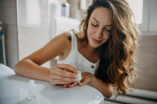 Young woman paints her nails