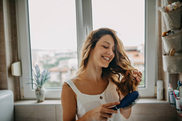 giovane donna che pettina i capelli - cura dei capelli foto e immagini stock