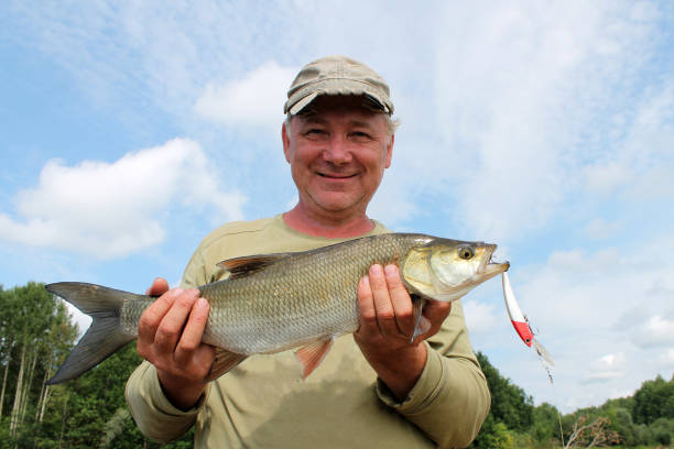 istock man holds caught fish in the sky 1251345676