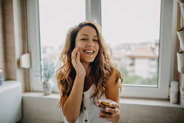 Young woman applies facial cream