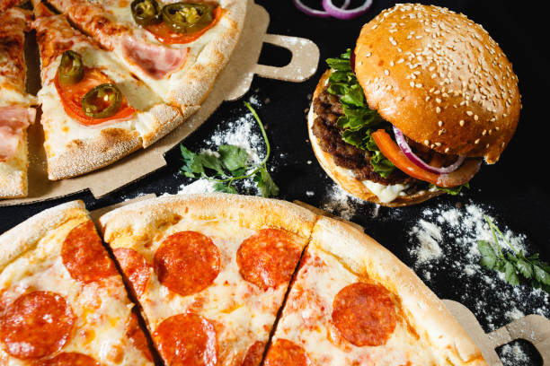 istock Pizza and burger on a black background. Top view 1251345845