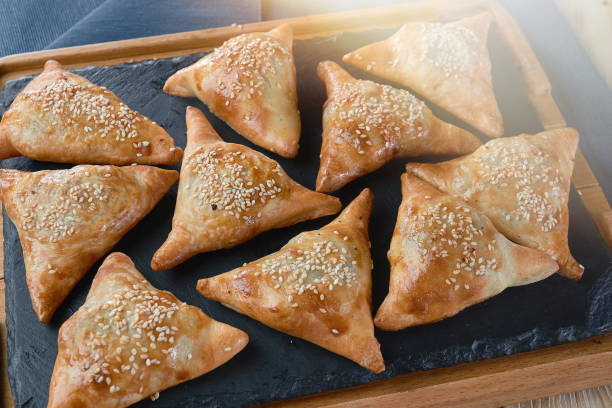 istock Uzbek dish - mini samosa with sesame seeds on a stone slab. Light effects 1251346362