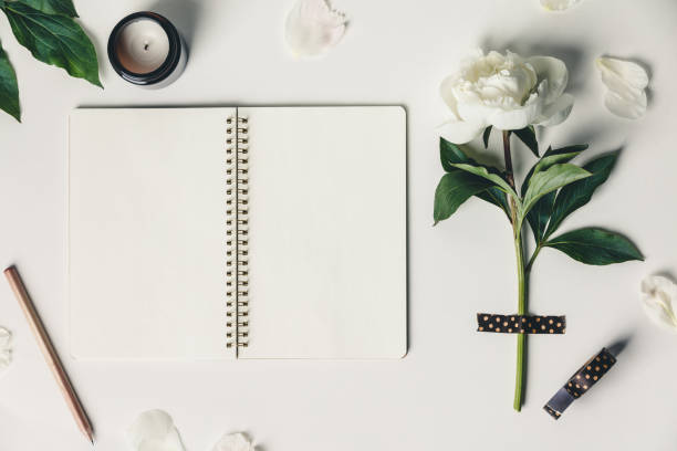 istock Flat-lay of Beautiful peony flower taped on white background and open notebook 1251349117