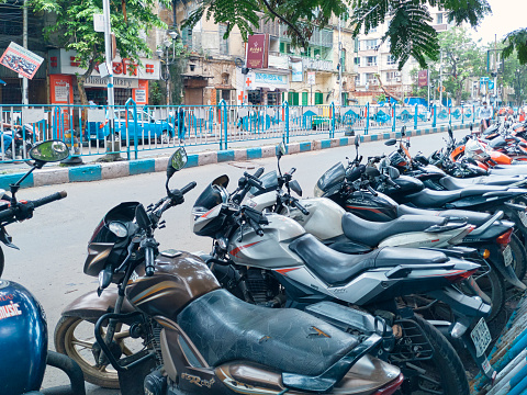 Lansdowne, Kolkata, 06/18/2020: A long queue of motorcycles parked at roadside, beside a city hospital. Those vehicles belongs to visitors / patients coming to hospital.