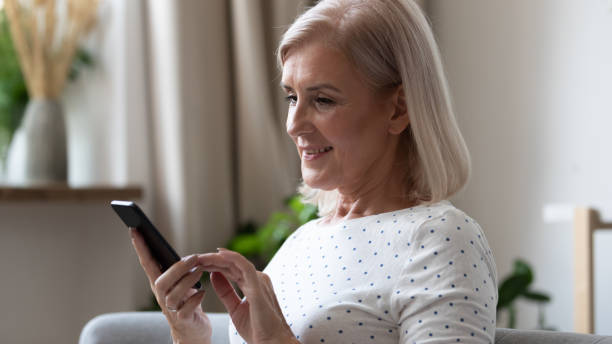 istock Smiling elderly woman using mobile applications at home. 1251349884
